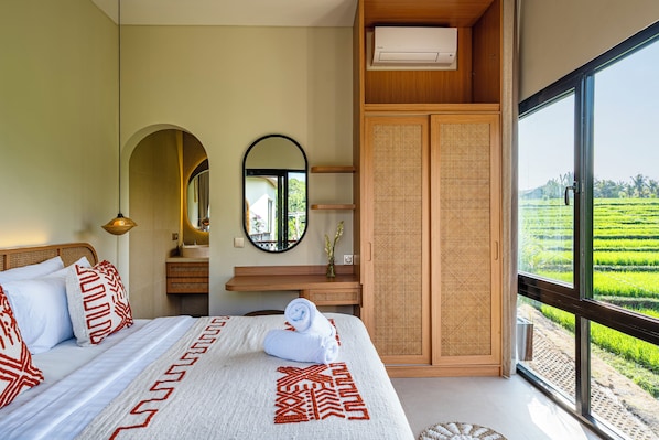 Un dormitorio con una cama grande, un espejo, un armario de madera y vistas a un campo verde.