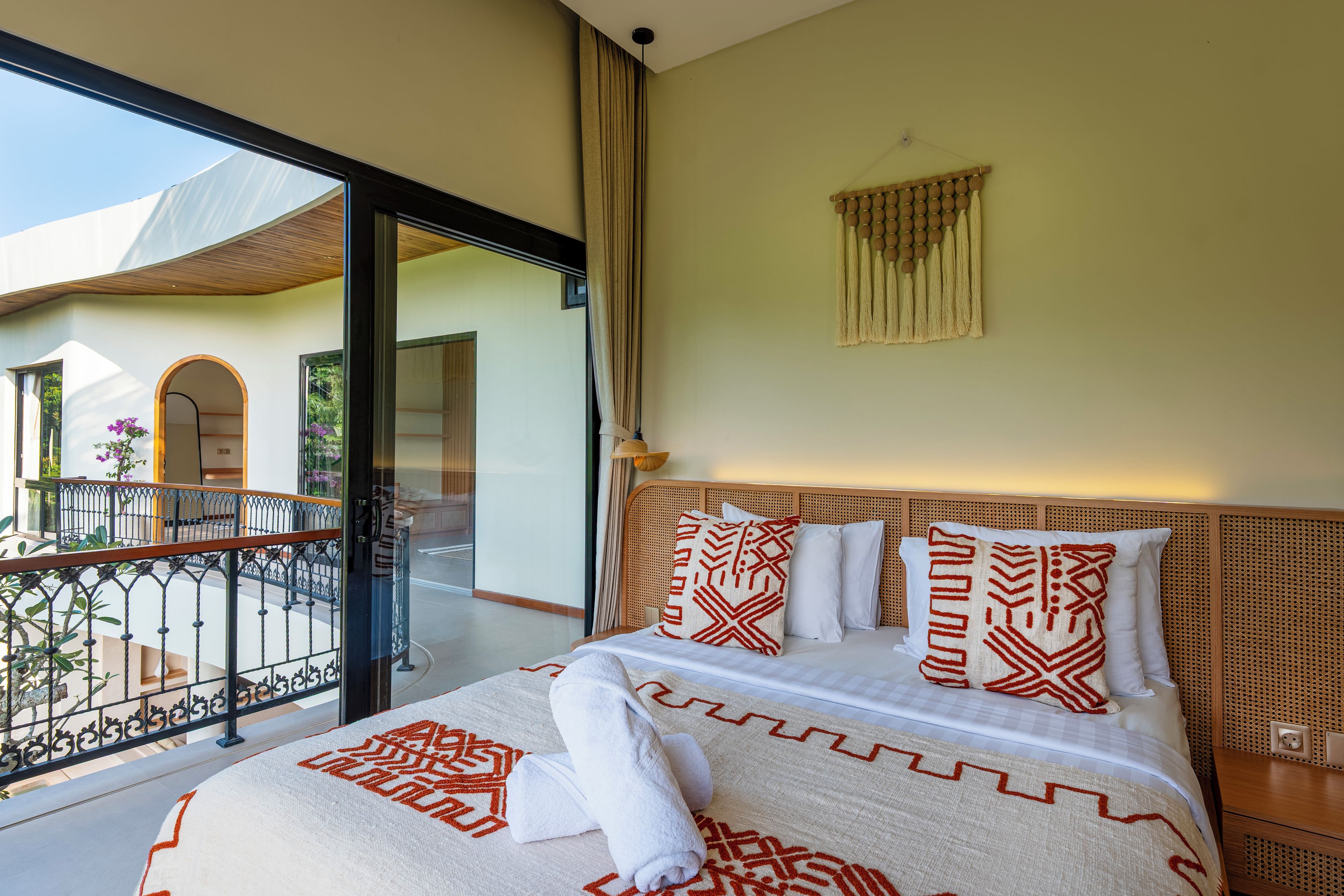 A hotel room with a bed, a balcony, and a view of the outside.