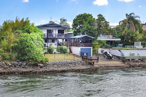 A waterfront property with a two-story building, a covered deck, and a boat dock. - BREEZE AT BROADBEACH - Elite Holiday Homes (Gold Coast)