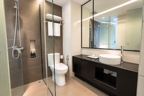 A modern bathroom with a glass-enclosed shower, a toilet, and a vanity with a large mirror. - Muraku Mega Kuningan Jakarta (Jakarta)