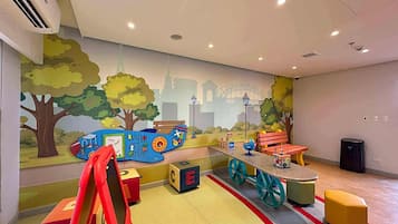 Un espace de jeux pour enfants agrémenté d’une fresque murale, d’aires de jeux et de sièges.