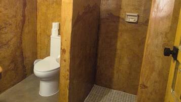 A bathroom with a toilet, a shower area, and a tiled floor.