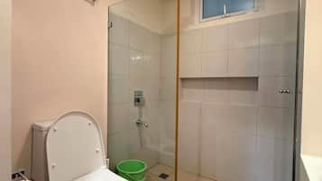 A bathroom with a toilet, a shower enclosure, and a sink.