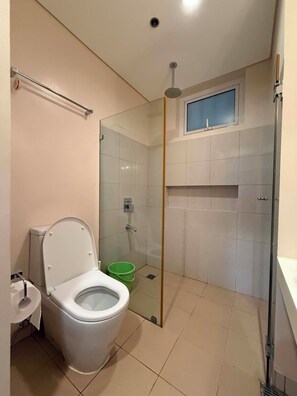 A bathroom with a toilet, a shower enclosure, and a sink. - Serene 1-bedroom condo with AC inside Pico De Loro Resort (Nasugbu)