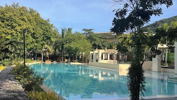 Una piscina con agua cristalina, rodeada de vegetación y un camino de piedra.