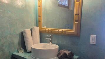 A bathroom with a white sink, a mirror with a wooden frame, and two wall-mounted lights.