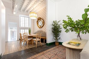 A dining area with a table and chairs, a mirror on the wall, and a potted plant. - Genteel Home Patio del Arenal 201 (Seville)