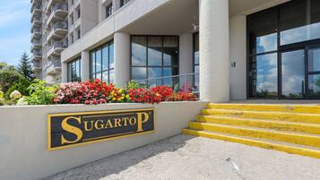 A hotel entrance with a sign reading 'Sugartop' and a set of yellow steps leading up to the entrance.