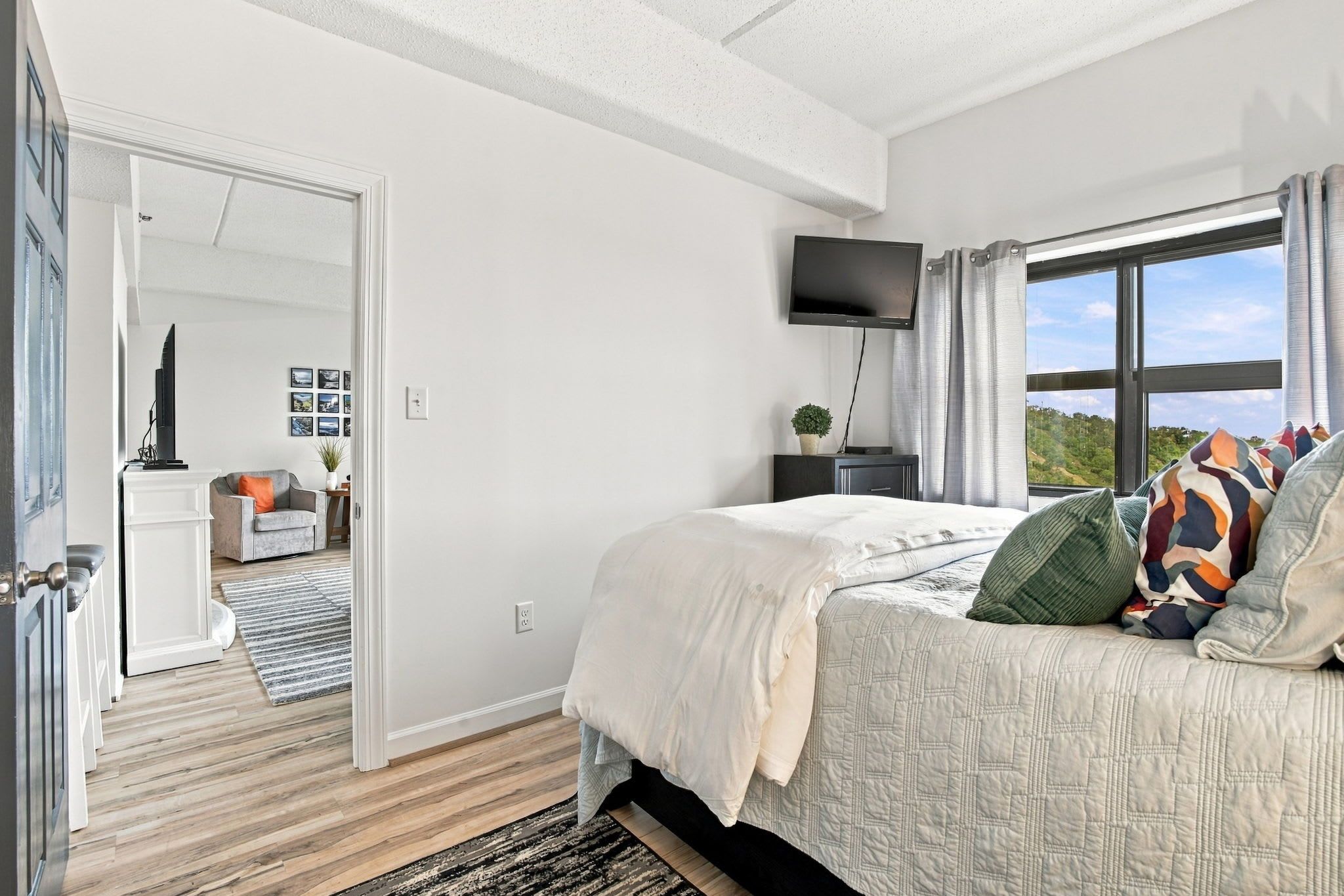 Une chambre à coucher avec un lit, une télévision, une fenêtre avec des rideaux et une vue sur l’extérieur.