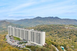 Un hotel su più piani con un parcheggio e montagne sullo sfondo.