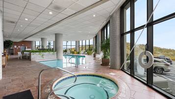 Una hall d'albergo con piscina, area relax e ampie finestre che offrono vista sul panorama esterno.