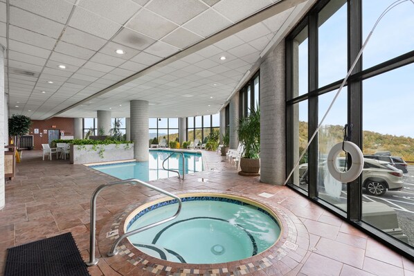 Una hall d'albergo con piscina, area relax e ampie finestre che offrono vista sul panorama esterno.