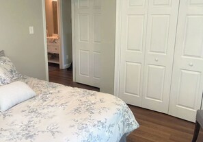 Ein Schlafzimmer mit Bett, Schrank und einem durchgehenden Tür sichtbaren Badezimmer.