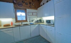 A kitchen with white cabinets, a window, a microwave, and a sink. - SPACIOUS DUPLEX WITHIN EASY WALKING DISTANCE OF BOTH CENTRAL ZERMAT & MATTERHORN (Zermatt)