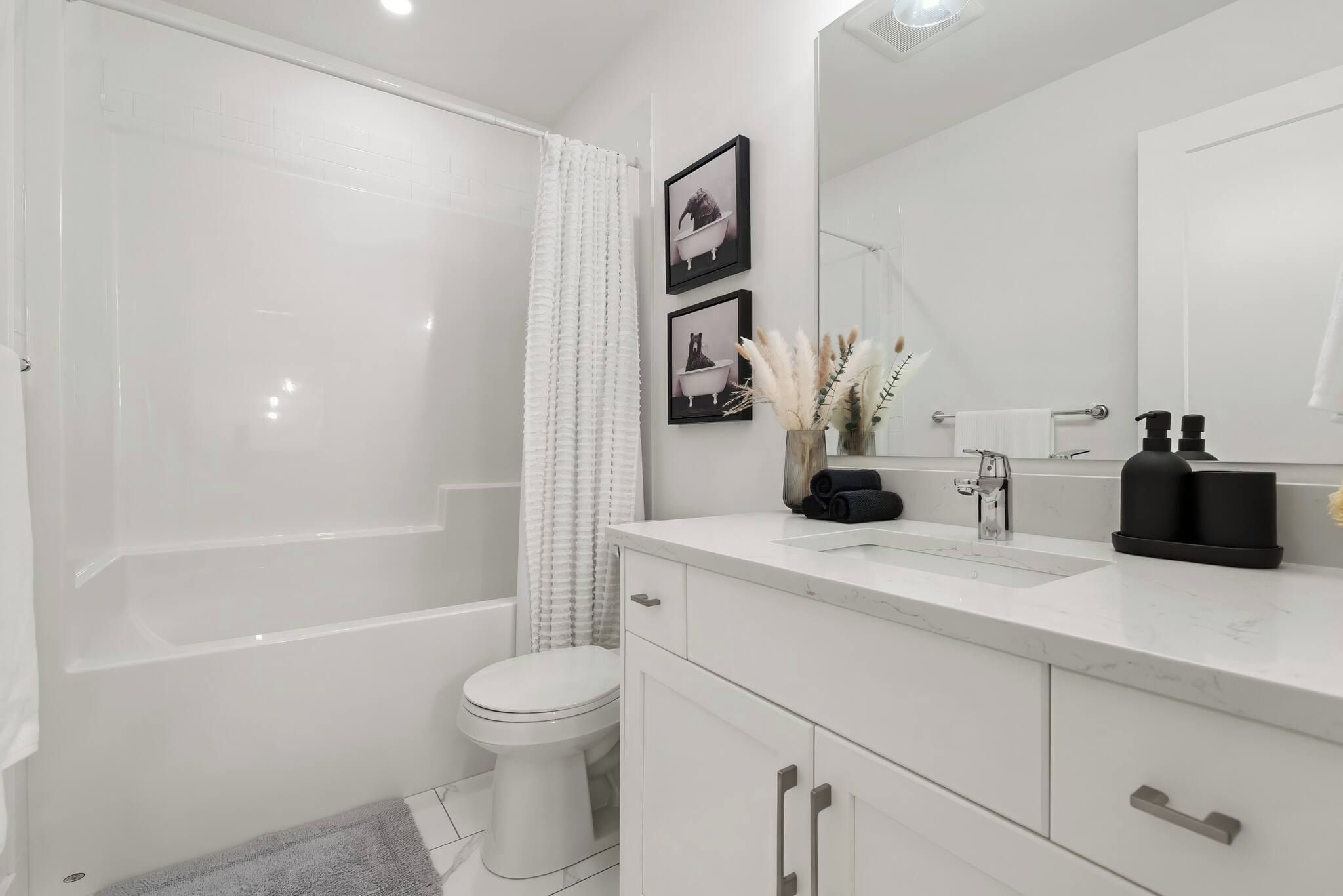 Une salle de bain moderne équipée d’une baignoire, de toilettes, d’un meuble-lavabo et d’un grand miroir.