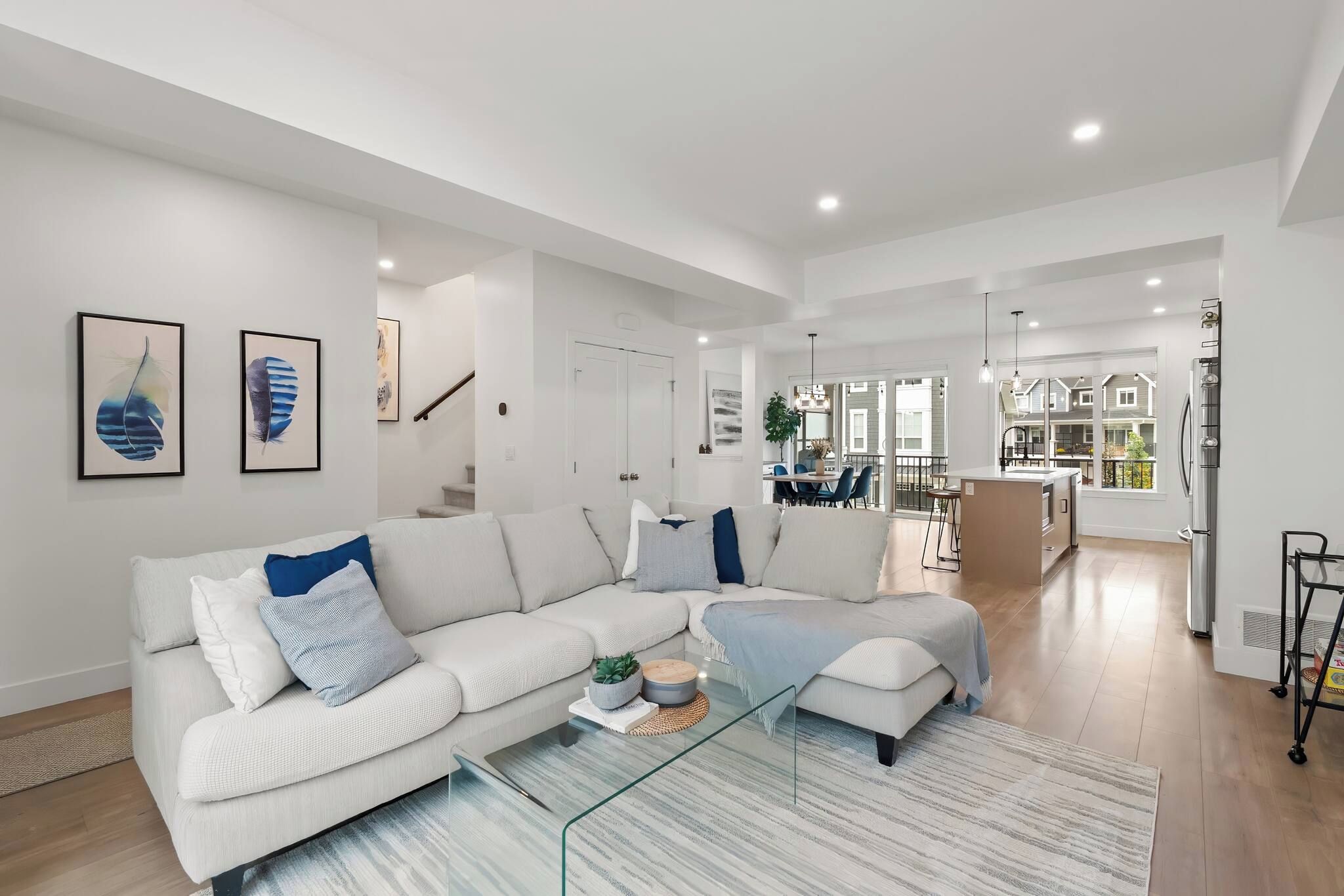 A modern living room with a sectional sofa, a glass coffee table, and a dining area in the background.