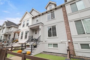 A row of modern townhouses with a central staircase, large windows, and a brick accent wall. - Foxfern Rowhome 4 Bed 3 Bath (Chilliwack)