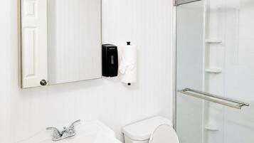 A bathroom with a white sink, toilet, and a glass shower enclosure.