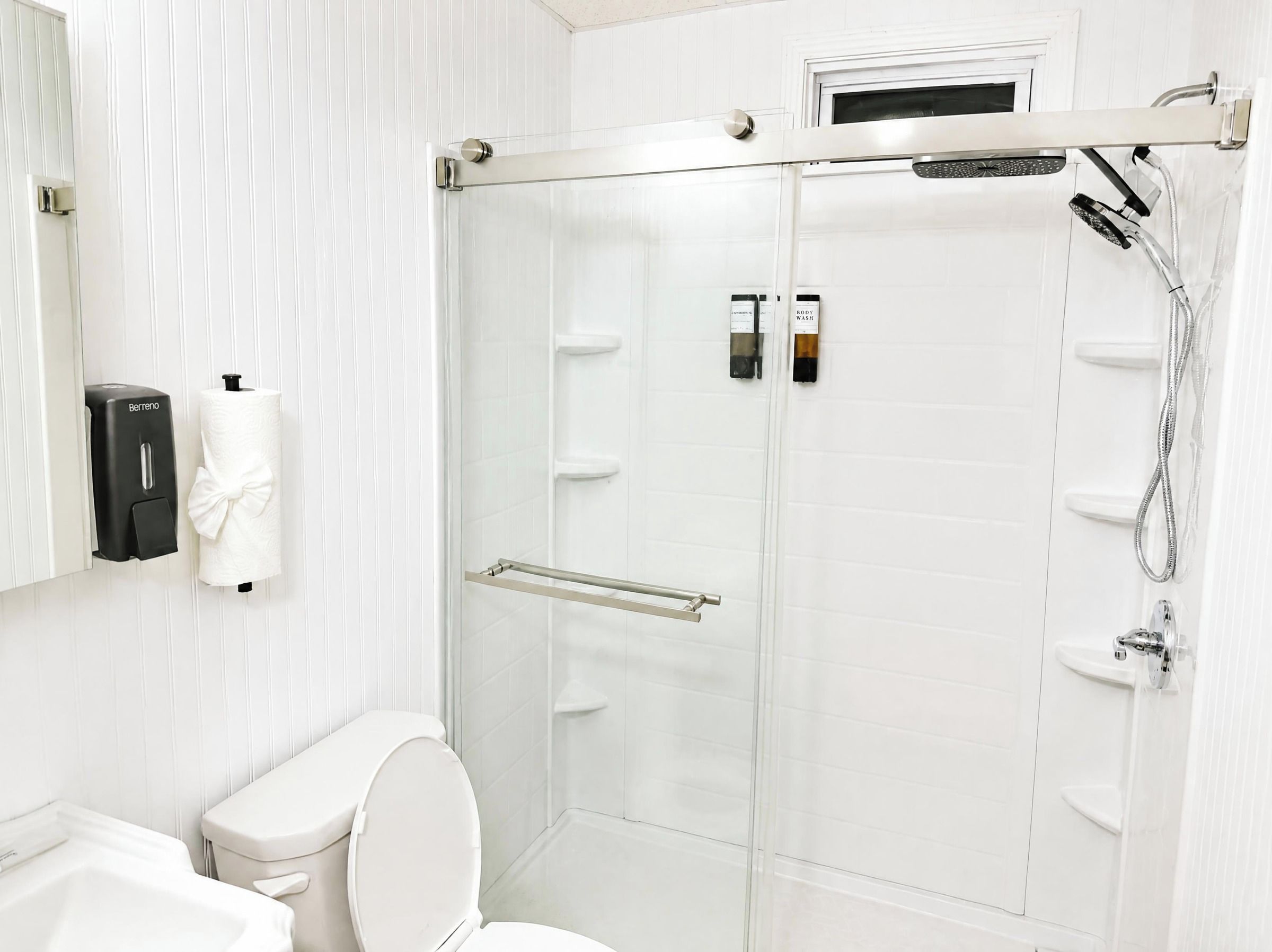 Een moderne badkamer met toilet, douchecabine en handdroger.