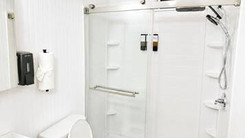 Een moderne badkamer met toilet, douchecabine en handdroger.
