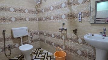 A bathroom with a toilet, bidet, sink, and shower.