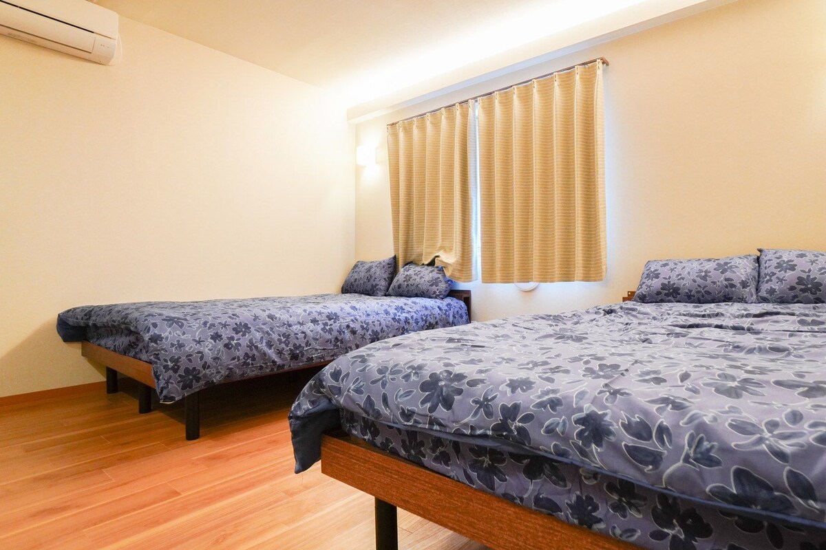 Ein Zimmer mit zwei Betten, einem Vorhangfenster und einer Klimaanlage.