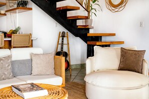 Ein modernes Wohnzimmer mit einer Couch, Sesseln, einem Couchtisch und einer Gitarre.