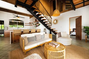 Ein geräumiger Wohnbereich mit einer großen Couch, einem runden Couchtisch und einer Treppe, die zu einer oberen Ebene führt.