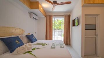 A hotel room with a bed, a ceiling fan, a TV, and a window with curtains.