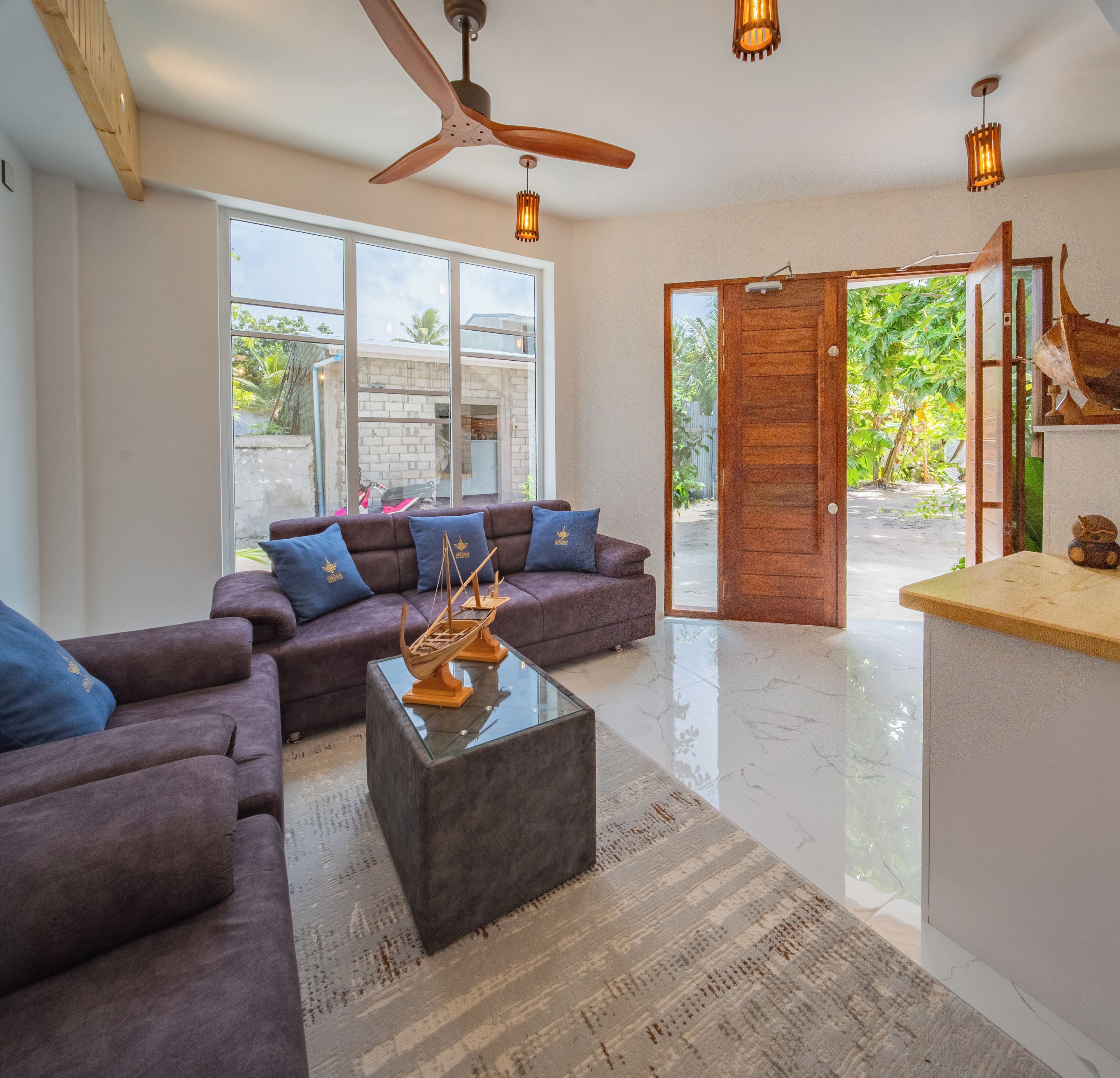 A modern living room with a sofa set, a coffee table, and a ceiling fan.