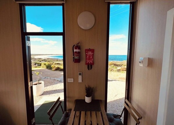 A room with a bench, a small table, a fire extinguisher, and a fire blanket on the wall.