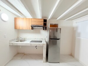 A compact kitchen with a built-in microwave, a stainless steel refrigerator, and a wooden cabinet above the countertop. - Cathedral Centro Histórico D12 (Guadalajara)