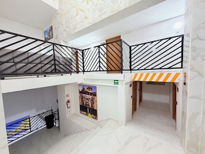 A multi-level interior with a staircase, a fire extinguisher, and a poster on the wall. - Cathedral Centro Histórico D12 (Guadalajara)