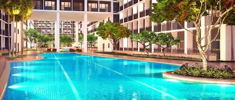 A swimming pool surrounded by a multi-story building with balconies.