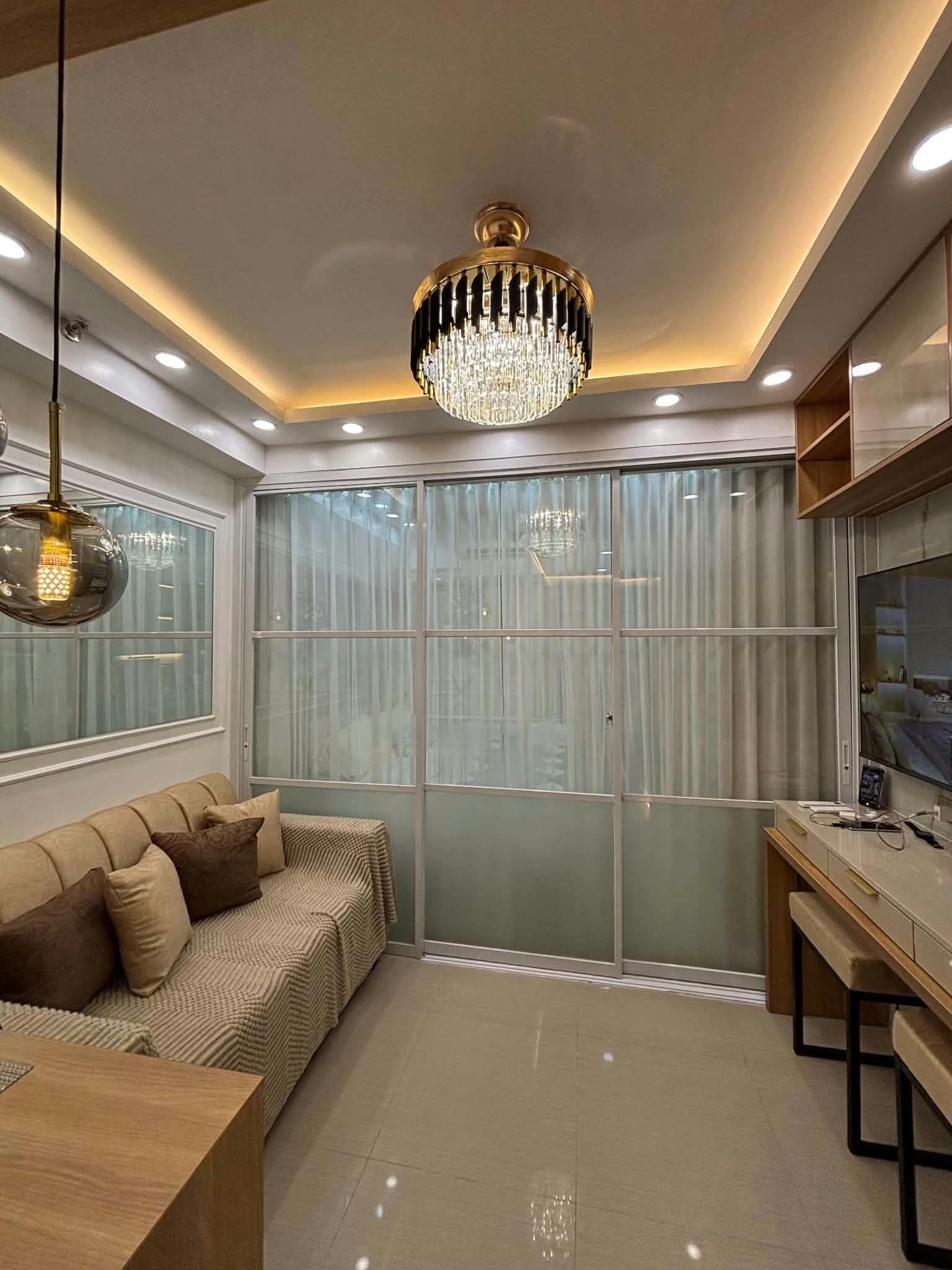 A modern interior with a sofa, a dining area, and a large window with curtains.
