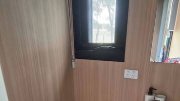 Een kleine badkamer met toilet, prullenbak en wastafel.