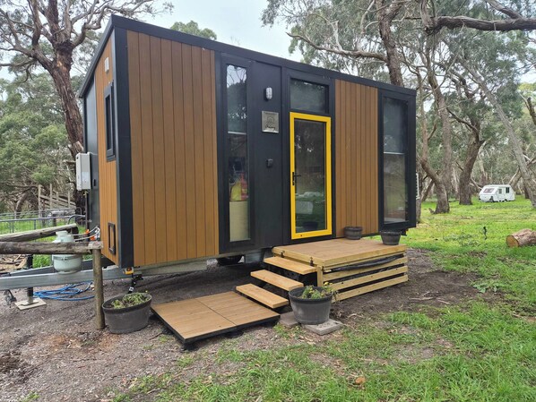 Een klein, modern vakantiehuisje met een houten gevel, een glazen deur en een klein terras.