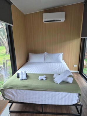Een hotelkamer met een bed, een groene dekbedovertrek, witte kussens en opgerolde handdoeken.