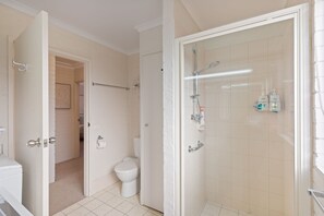 A bathroom with a toilet, a shower with a glass door, and a towel rack.