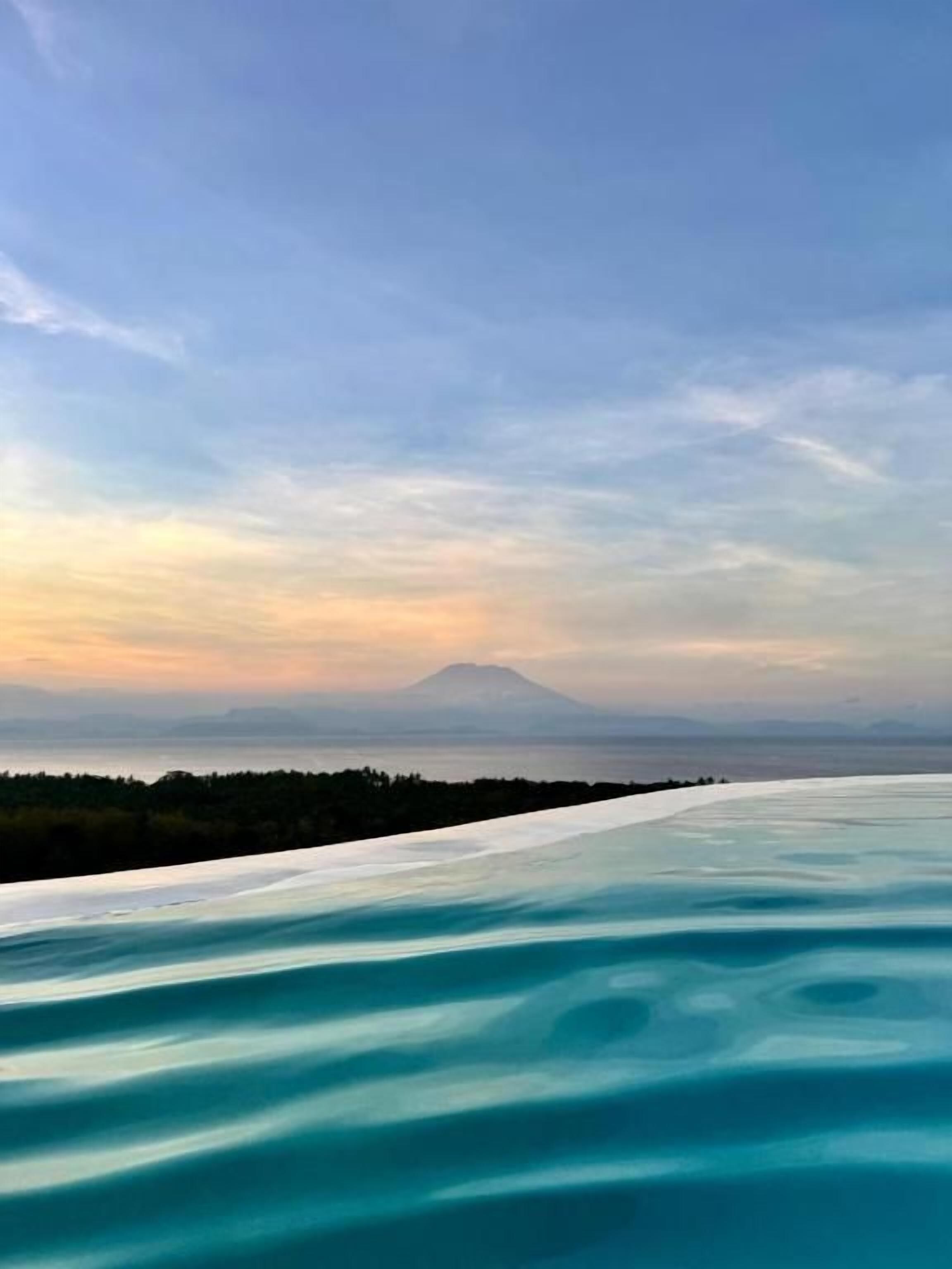 A panoramic view of a coastal landscape with a mountain in the distance.
