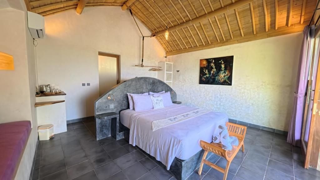 A bedroom with a bed, a chair, a shelf, and a painting on the wall.