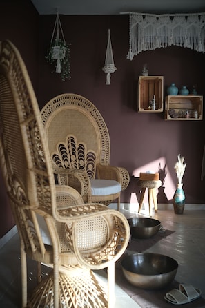 A wicker chair with a cushion, a wooden side table with a bowl, and a macramé wall hanging. - PENIDA VIEW VILLAGE (Penida Island)
