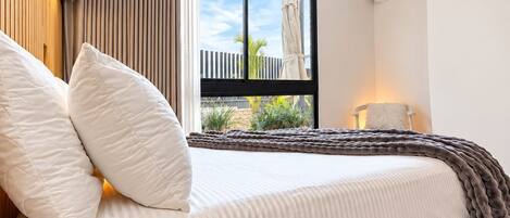 Un dormitorio moderno con una cama grande, una ventana con vistas al exterior y un equipo de aire acondicionado.