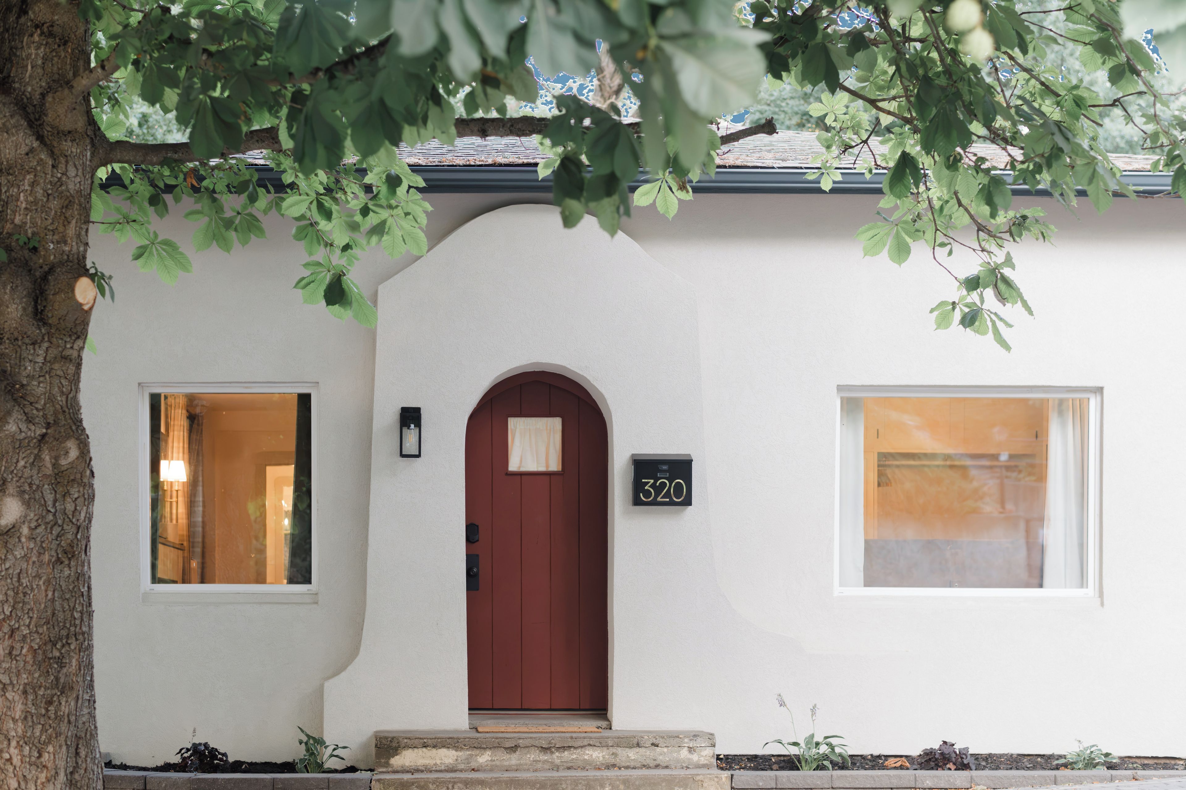 A house with a red door, a mailbox with the number 320, and two windows.