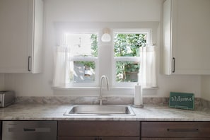 Una cocina con un lavabo, una ventana y un cartel de bienvenida.