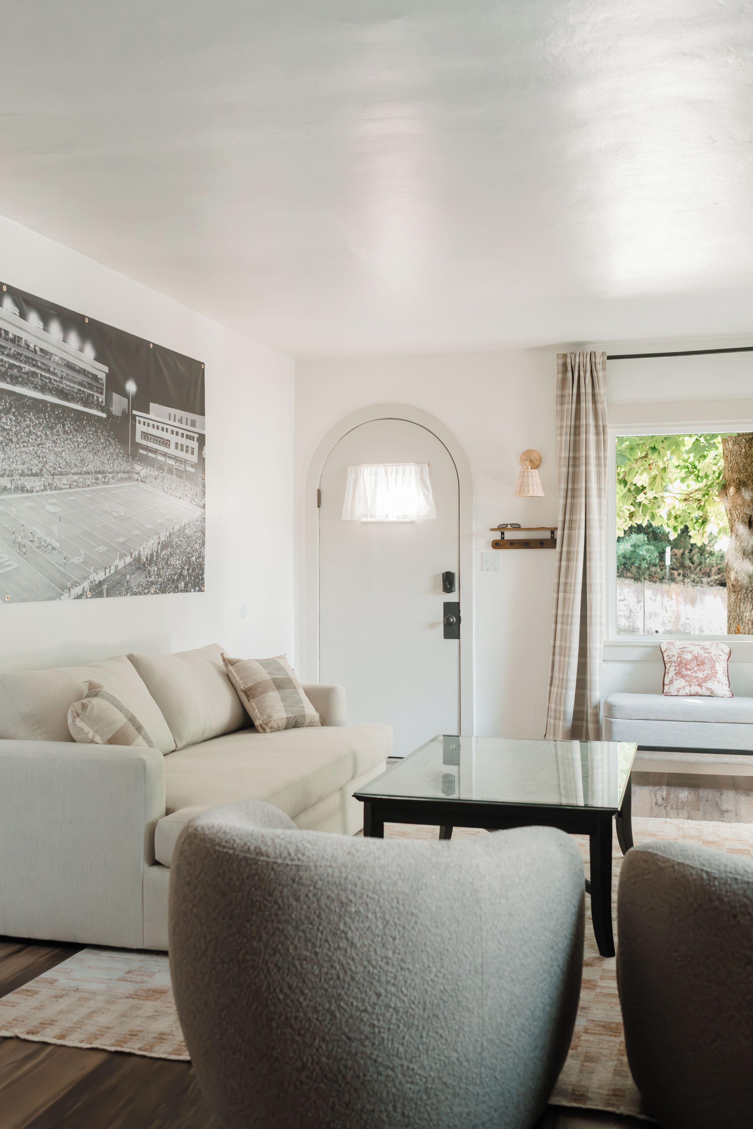 Ein modernes Wohnzimmer mit einem weißen Sofa, einem Glastisch und einem großen Poster an der Wand.