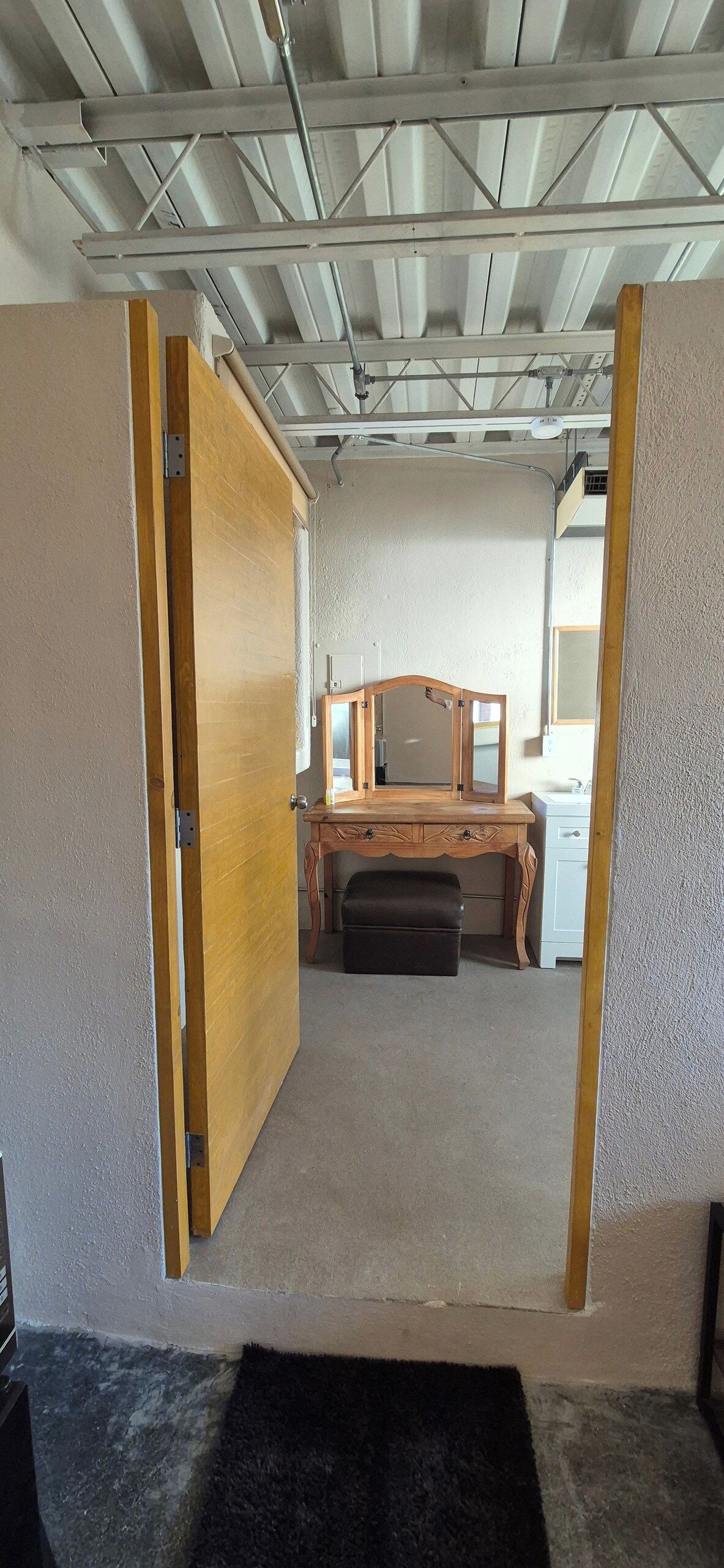A room with a wooden desk, a bench, and a white cabinet.