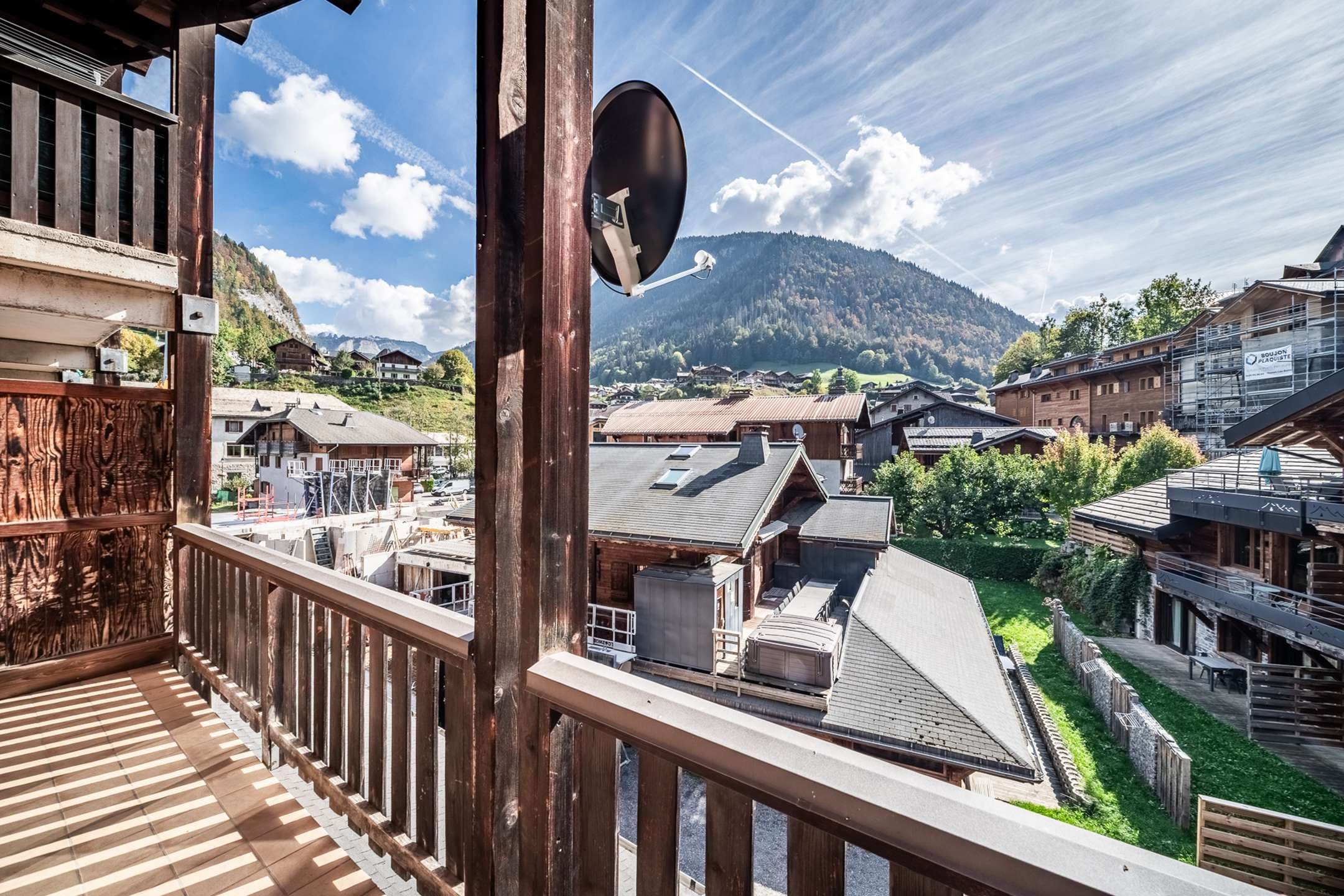A wooden balcony with a view of a mountain and traditional buildings.