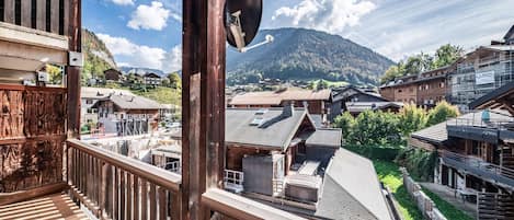 A wooden balcony with a view of a mountain and traditional buildings.