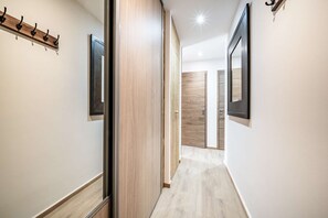A hallway with wooden doors, a coat rack, and a light-colored floor. - JANIN 5 Charming renovated apartment 1 bedroom + cabin (MORZINE)